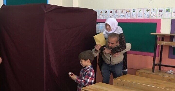 ناخب تركي يحمل والدته المسنة على ظهره متوجهًا لصناديق الاقتراع في الجولة الثانية